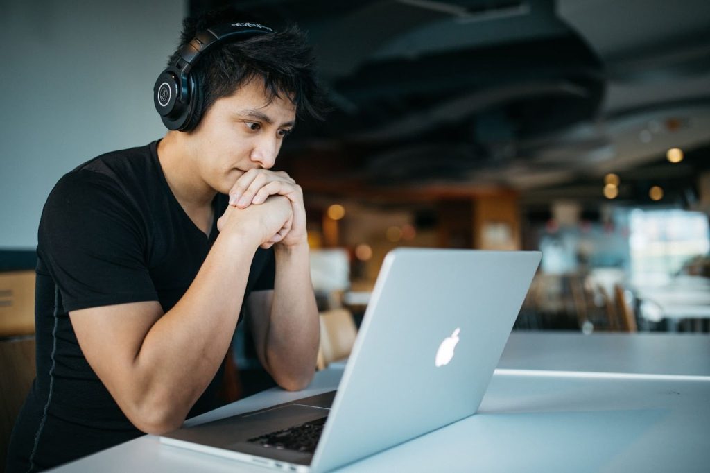 Gambar menunjukkan seorang lelaki fokus di hadapan laptop di sebuah kafe.